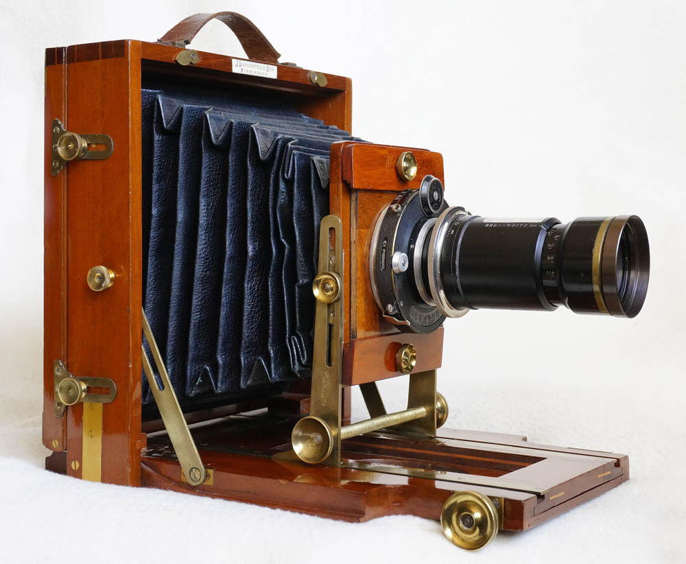 Deskový přístroj formátu 13x18 cm z mahagonu firmy J. Lancaster & Son Birmingham z roku 1897 má již prakticky všechny vymoženosti profesionálních systémových velkoformátových kamer: výškový i sklopný pohyb výměnných objektivů a kipování se zadní stěnou s možností vkládaní kazet bez sejmutí matnice. Na snímku je osazen unikátním tele-zoomem Telinear 540-1080 mm což je důkazem, že konstrukce zoomů byla známá už v 19. století.  O rok později firma vyrábí už 200 000 fotoaparát (zanikla v roce 1955).. O rok později firma vyrábí už 200 000 fotoaparát (zanikla v roce 1955)..